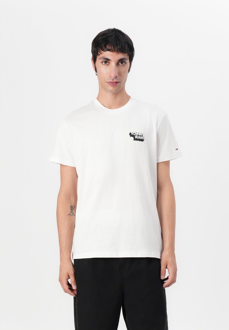 White cotton T-shirt with short sleeves, round neck, featuring a black printed logo on the left chest and a small embroidered accent on the sleeve.