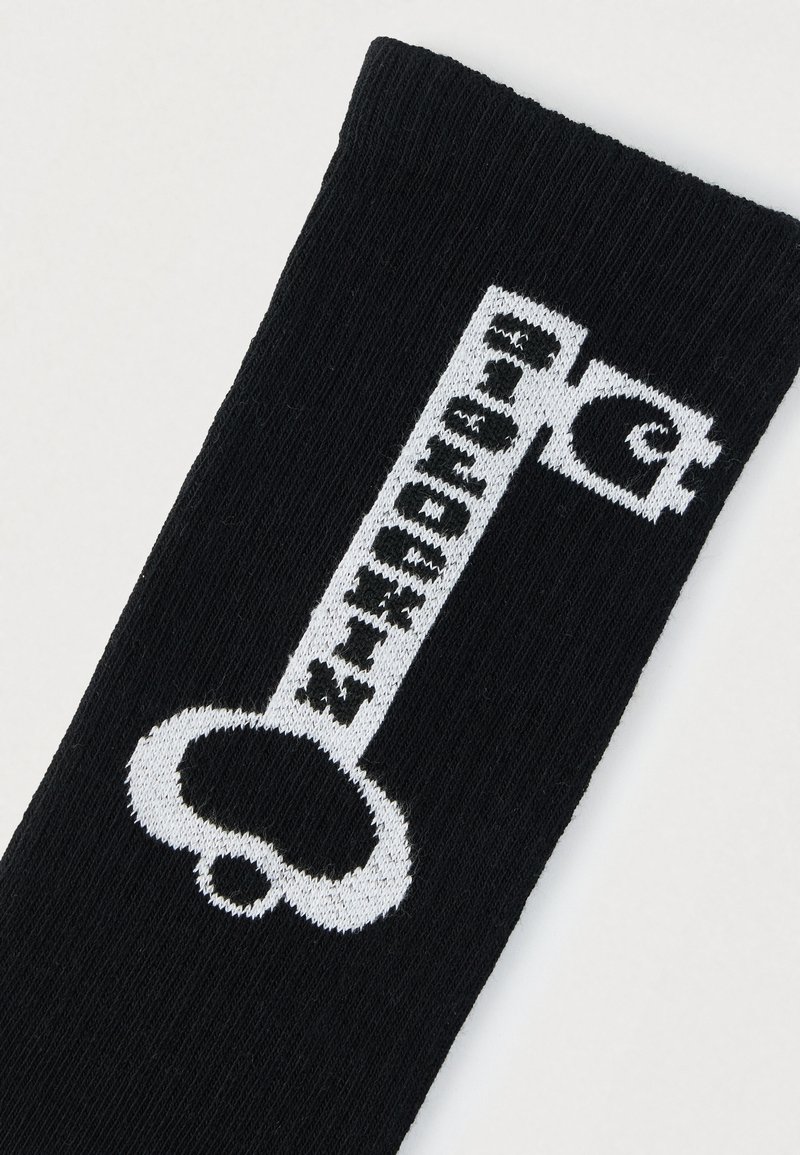 Schwarze Socke mit einem auffälligen weißen Grafikdesign, das Text und ein Symbol oben zeigt. Das Material wirkt weich mit gerippter Struktur.