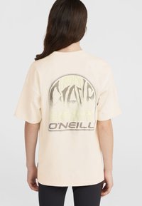 Le t-shirt à manches courtes couleur pêche présente un grand design graphique au dos avec le texte "O'Neill" et un art stylisé en gris et vert néon.