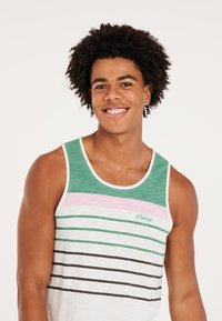 Groene en witte mouwloze tanktop met horizontale strepen; beschikt over roze en zwarte strepen, en een klein logo geborduurd op de borst.