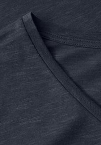 Ciemnoszara bawełniana tkanina o gładkiej fakturze, z dekoltem w serek oraz starannie wykończonymi krawędziami. Widoczny subtelny melanż.