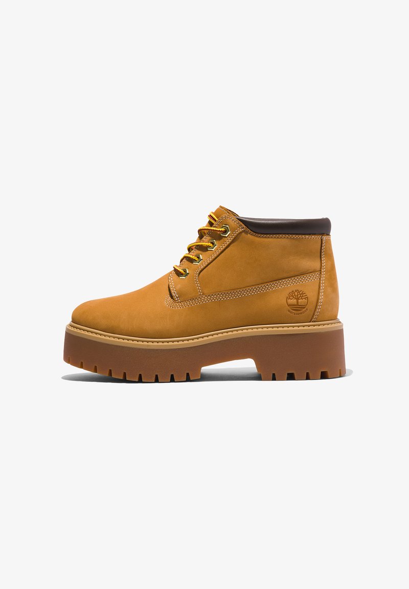Brune lær ankle boots med rund tå, brune accenter, tyk platformsål og kontrasterende gule snørebånd. Har et logo på siden.