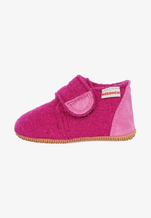 Chausson en feutre rose avec une sangle velcro et des accents en daim, présentant une semelle texturée pour une meilleure adhérence. Étiquette de la marque visible sur le côté.