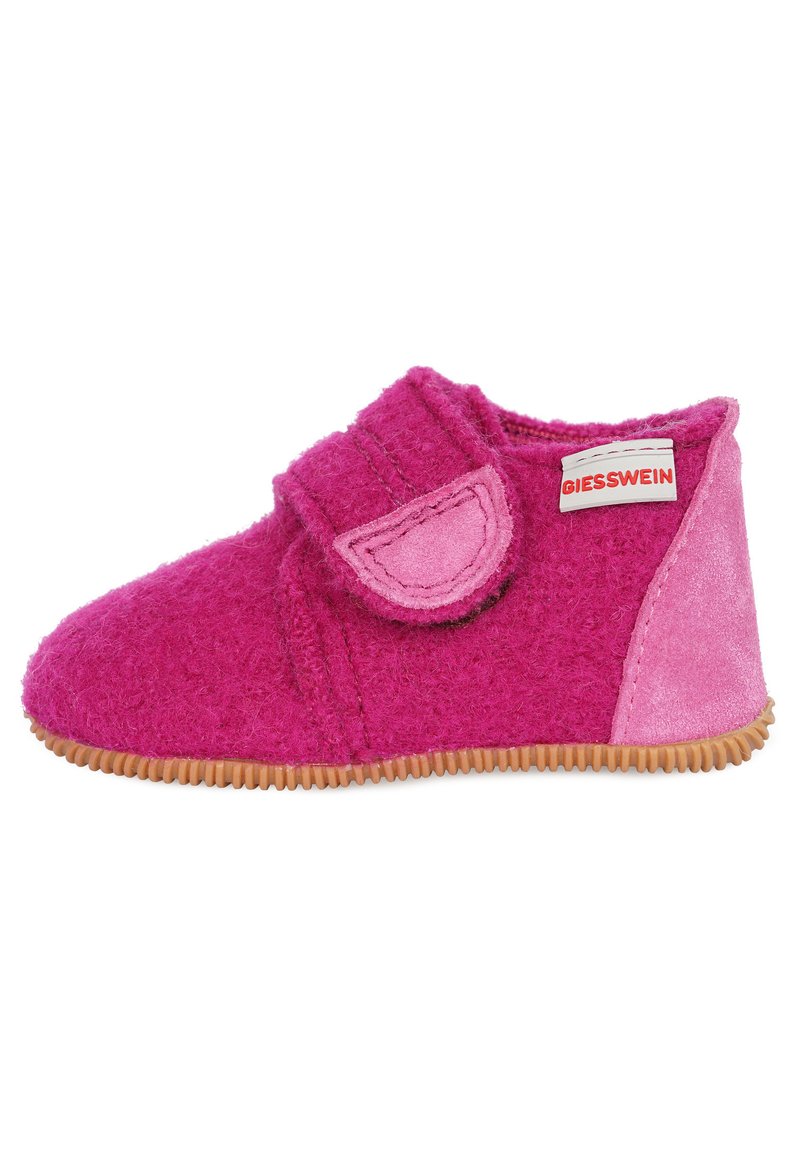 Chausson en feutre rose avec une sangle velcro et des accents en daim, présentant une semelle texturée pour une meilleure adhérence. Étiquette de la marque visible sur le côté.