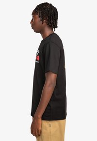 Zwarte katoenen T-shirt met een grafisch ontwerp op de voorkant. Ronde hals, korte mouwen, standaard pasvorm en zijventdetail.