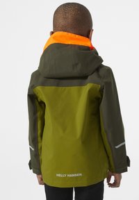 Groene en grijze waterdichte jas met een oranje kraag, reflecterende accenten en een logo op de achterkant. Zichtbare naden en verstelbare manchetten.