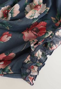 Květinová chiffon látka v námořnické modři s velkými růžovými a červenými květinami. Spodní část má volánový okraj s jemným šitím.