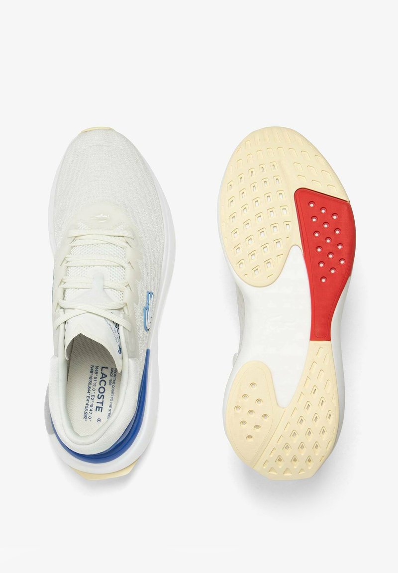 Chaussures de sport Lacoste en maille écrue, présentant un dessus texturé, des accents bleus et une semelle en caoutchouc multicolore avec des sections rouges et beige.