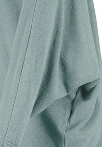 Weicher, türkisfarbener Strickpullover mit einem lockeren Schnitt, fallendem Stoff und gerippten Bündchen, der mit einer strukturierten Oberfläche visuelles Interesse erzeugt.