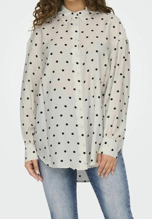 Langarm-Hemd in hellem Creme mit schwarzen Punkten. Mit klassischem Kragen und geknöpften Ärmeln, aus leichtem Stoff gefertigt.