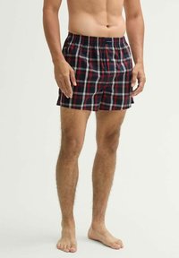 Männer Shorts aus kariertem Stoff in Navy, Rot und Weiß, mit einem elastischen Bund und lockerer Passform. Hergestellt aus leichtem Material mit einem karierten Muster.