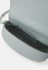 Světle modrá kožená kabelka přes rameno se hladkým povrchem, obsahující přední klopu a jeden vnitřní prostor s přihrádkou na karty.