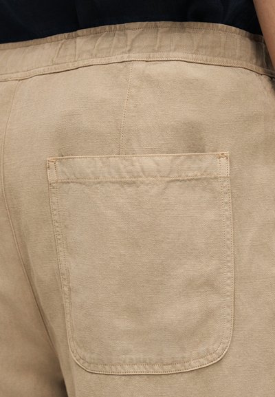 Μπεζ βαμβακερό παντελόνι με πίσω τσέπη και υφασμάτινη ζώνη μέσης με υφή. Το υλικό έχει μια ελαφριά λάμψη, που βελτιώνει τη συνολική του εμφάνιση.