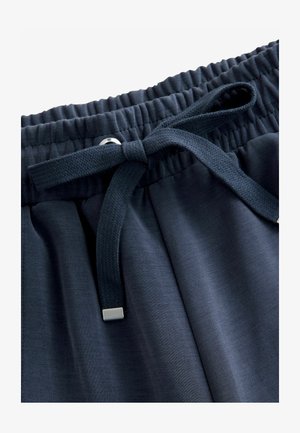 Marineblaue Hosen aus glattem Stoff mit einem elastischen Bund und einem flachen Kordelzug, die am Ende eine metallische Akzentuierung haben.