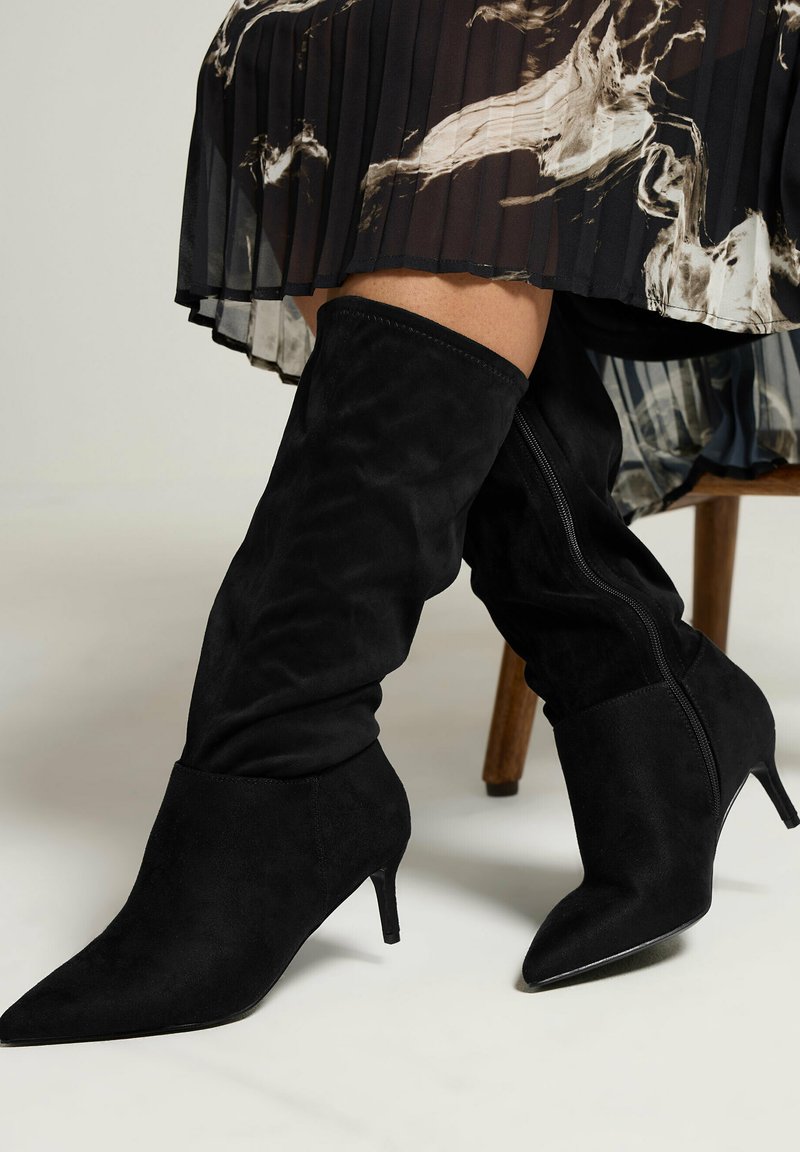 Stivali alti in suede nero con punta affilata e tacco a stiletto, caratterizzati da una texture liscia e una zip laterale.