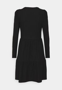 Robe noire à manches longues avec texture côtelée, corsage ajusté et jupe à volants. Encolure ronde et manches froncées ajoutent des détails.