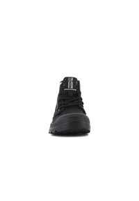 Sneaker nera con design alto, caratterizzata da accenti arancioni, suola testurizzata e un'etichetta con logo sulla linguetta. Chiusura anteriore con lacci.
