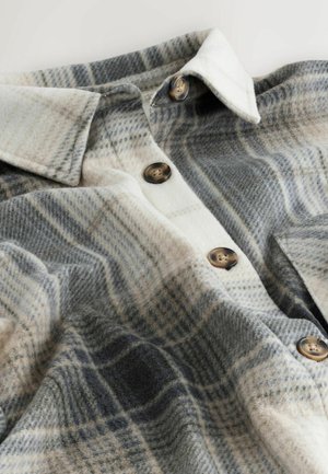 Plaid flannel shirt in shades of gray, cream, and brown with button closures, and a soft texture. Features a classic collar and a relaxed fit.