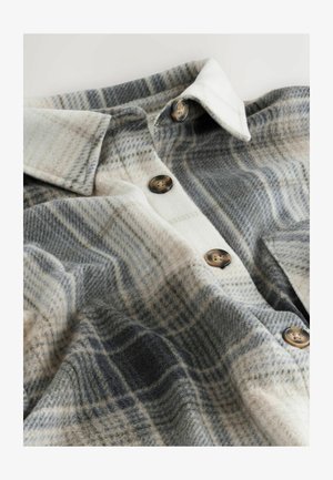 Plaid flannel shirt in shades of gray, cream, and brown with button closures, and a soft texture. Features a classic collar and a relaxed fit.