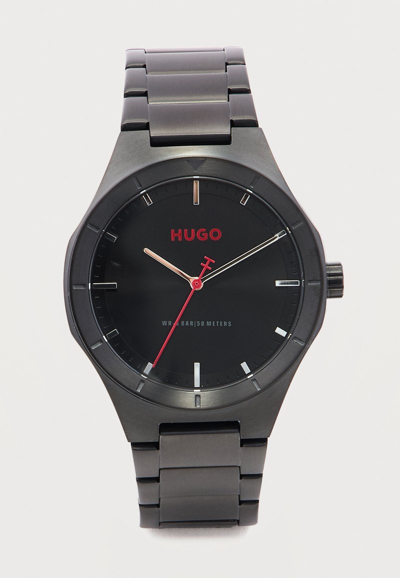 Montre-bracelet en métal noir avec aiguille des secondes rouge, logo Hugo, et résistance à l'eau jusqu'à 50 mètres sur un bracelet à maillons.