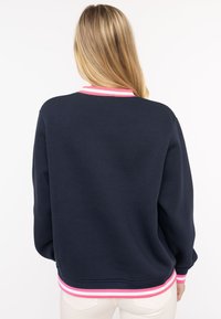 Marineblauer Pullover mit rosa-weißer gestreiftem Rippenkragen und -bündchen. Weicher Stoff, lockere Passform, schlichtes Rückendesign, keine sichtbaren Grafiken oder Muster.