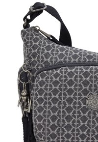 Gray patterned shoulder bag with a textured fabric, zippered main compartment, silver hardware, and a charm detail attached to the zipper.