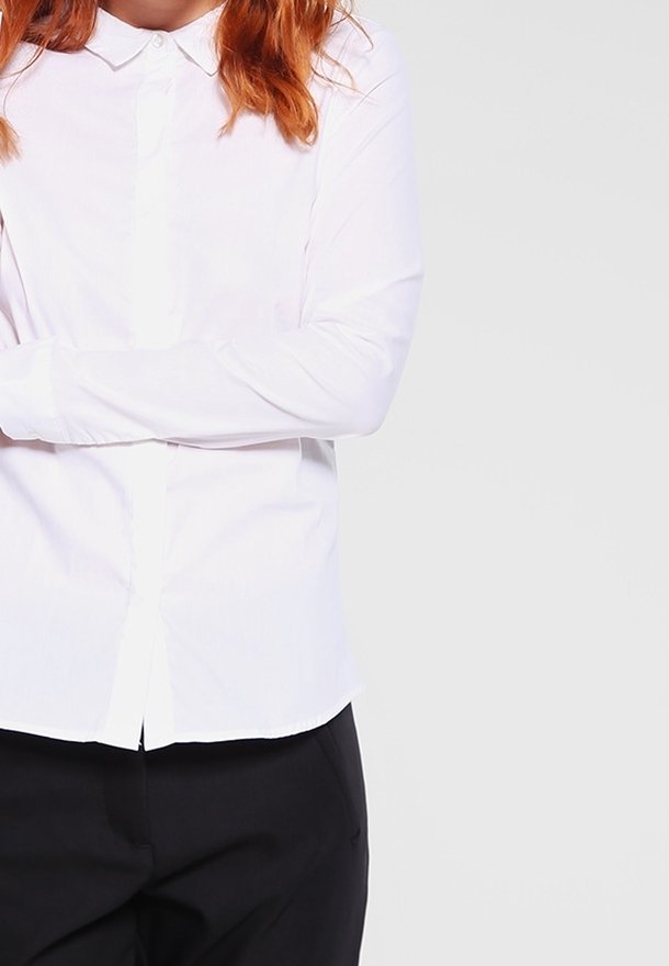 Vit långärmad skjorta med krage och knäppning framtill, tillverkad i ett slätt, något strukturerat tyg och med en skräddarsydd passform.