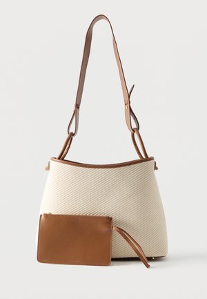 Sac à main tissé beige avec garniture en cuir marron, bandoulière réglable et pochette zippée assortie en cuir marron à l'avant.