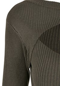 Top en tricot côtelé de couleur vert olive foncé, présentant un design découpé unique à l'épaule, une texture lisse et une silhouette ajustée.