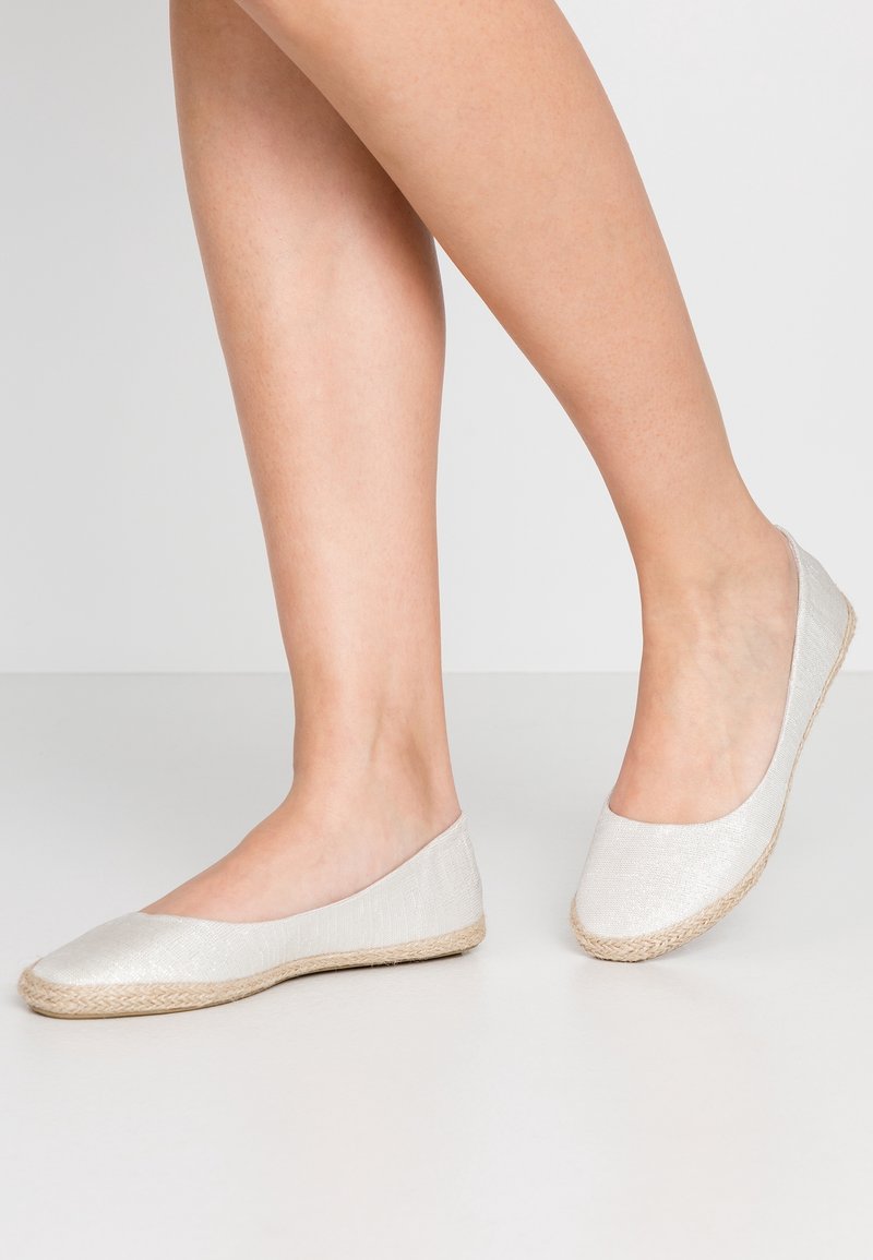 Chaussures plates beige clair avec dessus en tissu texturé, bout rond et semelle en jute tissé, au design simple.
