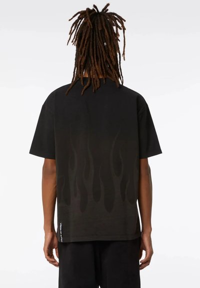 T-shirt nera a maniche corte con un sottile motivo a fiamma in tonalità più scure. Realizzata in un materiale morbido, ha una vestibilità comoda.