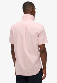 Korte mouwen shirt in lichtroze, gemaakt van een textuurstof, met een staande kraag en een centrale achterplooi voor gemakkelijke beweging.