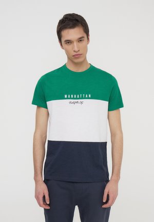 T-shirt a blocchi di colore verde, bianco e blu navy. Presenta un colletto girocollo e la scritta stampata "MANHATTAN" sul petto. Maniche corte.