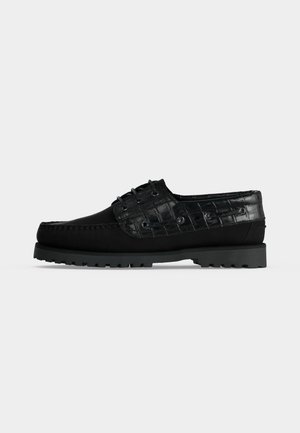 Chaussure bateau cuir noire pour homme à lacets, avec un motif crocodile texturé sur les côtés et à l'arrière, et une semelle épaisse à crampons.