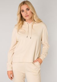 Beige capuchon sweatshirt met lange mouwen, voorzak en trekkoordaccenten. Zachte stof en relaxte pasvorm. Geen zichtbare patronen.