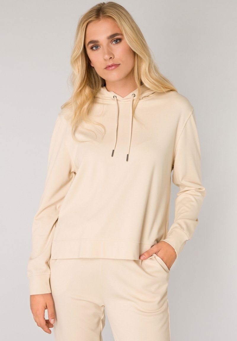 Beige capuchon sweatshirt met lange mouwen, voorzak en trekkoordaccenten. Zachte stof en relaxte pasvorm. Geen zichtbare patronen.