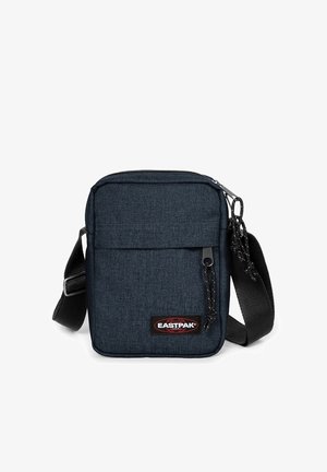 Kompaktní tmavě modrá crossbody taška s černým nastavitelným popruhem, přední kapsou na zip a nášivkou Eastpak.