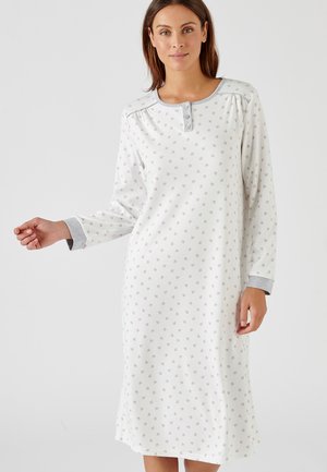 Camicia da notte a maniche lunghe di colore bianco con un piccolo motivo floreale. Presenta una patta con bottoni grigia e dettagli grigi sui polsini. Tessuto morbido.