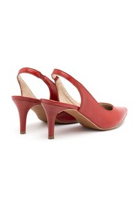 Zapatos de slingback de cuero rojo con punta afilada, tacón cónico de 6 cm y detalles laterales recortados. Textura suave con una plantilla neutra.