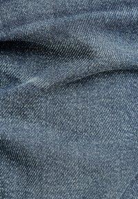 Denim fabric in dark blue with a soft texture. The surface shows a fine weave pattern and subtle variations in color, enhancing depth.