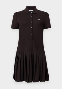 Robe polo noire à manches courtes avec patte de boutonnage, col, jupe plissée et petit logo de crocodile vert brodé sur la poitrine.