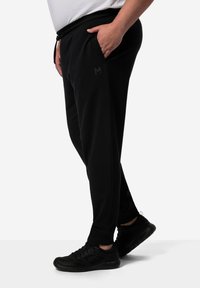 Zwarte joggers gemaakt van zachte stof, met een elastische taille, zijzakken en een klein logo op de linker bovenbeen. Gekocht met zwarte sneakers.