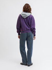 Μωβ φούτερ με γκρι κουκούλα, διαθέτει άνετη εφαρμογή. Συνδυάζεται με χαλαρά μπλε τζιν παντελόνια, με ορατές τσέπες και μαύρες ankle μπότες.