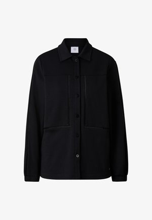 Veste noire boutonnée avec col, manches longues, deux grandes poches avant et des détails de couture subtils le long des coutures et des bords des poches.