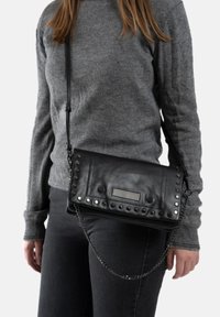 Zwarte leren schoudertas met studdetails en een kettingriem. Heeft een rechthoekige sluiting en een gestructureerd oppervlak.