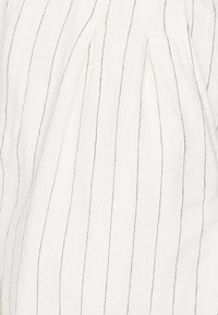 Tela blanca con finas rayas verticales negras; textura suave; presenta pliegues que aportan dimensión y movimiento al diseño general.