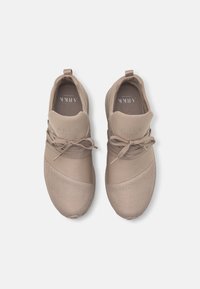 Beige Sportchuhe mit einer glatten Oberseite und Mesh-Details. Sie verfügen über flache Schnürsenkel, einen gepolsterten Schaft und eine strukturierte Zehenkappe.