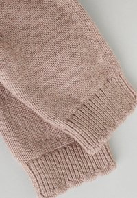 Chauffe-bras tricotés dans une douce teinte rose, présentant un poignet côtelé et un bord festonné, exposés côte à côte sur un fond neutre.