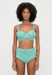 Τουρκουάζ μπικίνι δύο κομματιών με λαμπερή υφή; το τοπ διαθέτει βάσεις στήθους και ρυθμιζόμενες τιράντες, ψηλόμεσα σλιπ με λεπτομέρεια ζώνης.