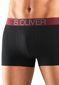 Crne bokserice s tamnocrvenim elastičnim pojasom na kojem se nalazi logo "S.OLIVER" u sivoj boji. Izrađene su od glatkog, rastezljivog materijala.